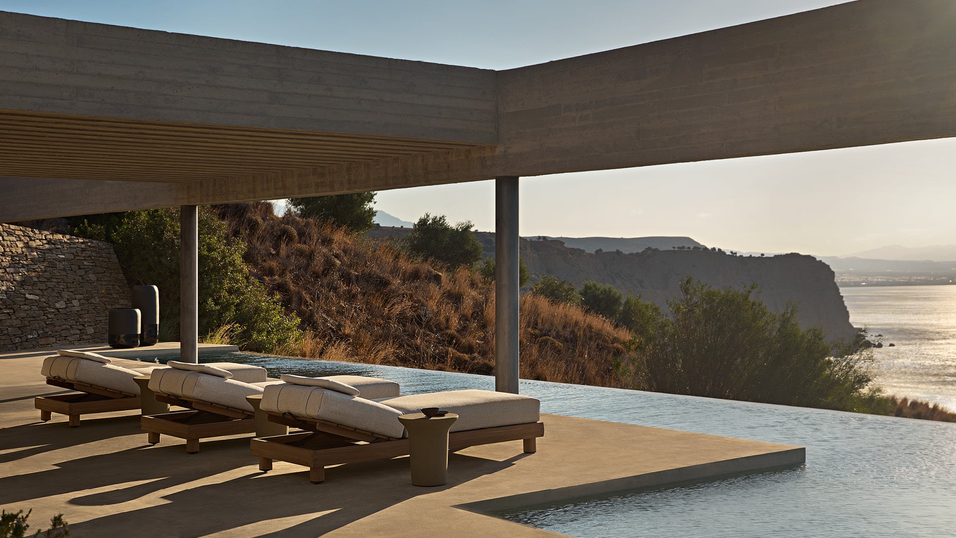 Ambiente exterior en una villa moderna, zona de piscina con tumbonas Ketch, mesa auxiliar Reef en Cementoraw® menta.