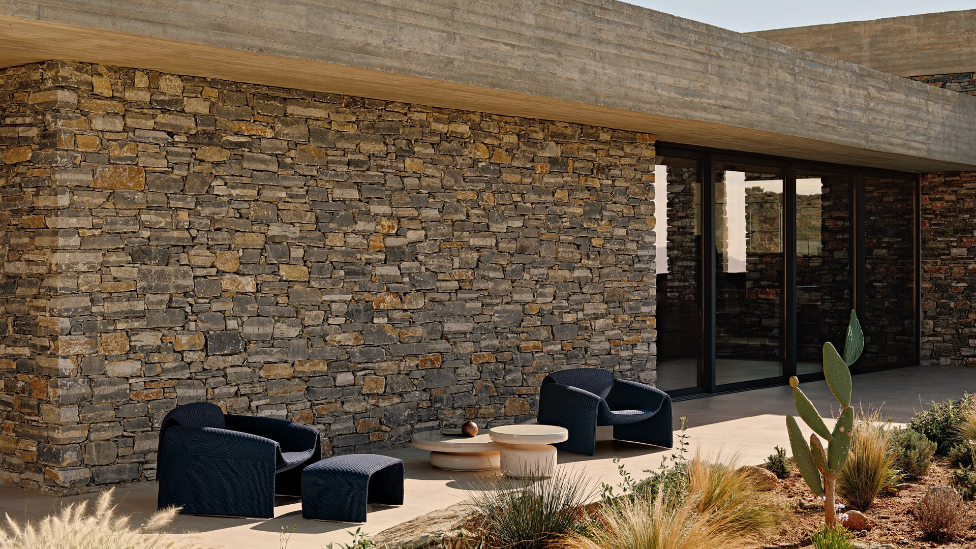 Modernes Outdoor-Ambiente mit dem Sessel Le Club und den couchtisch Crew.